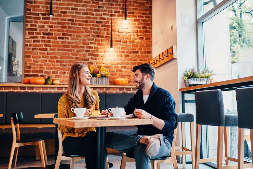 Picture of young couple dating at cafe. Young woman and man at coffee shop.