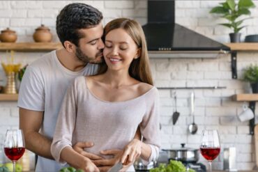man holding woman and kissing her endearingly in kitchen