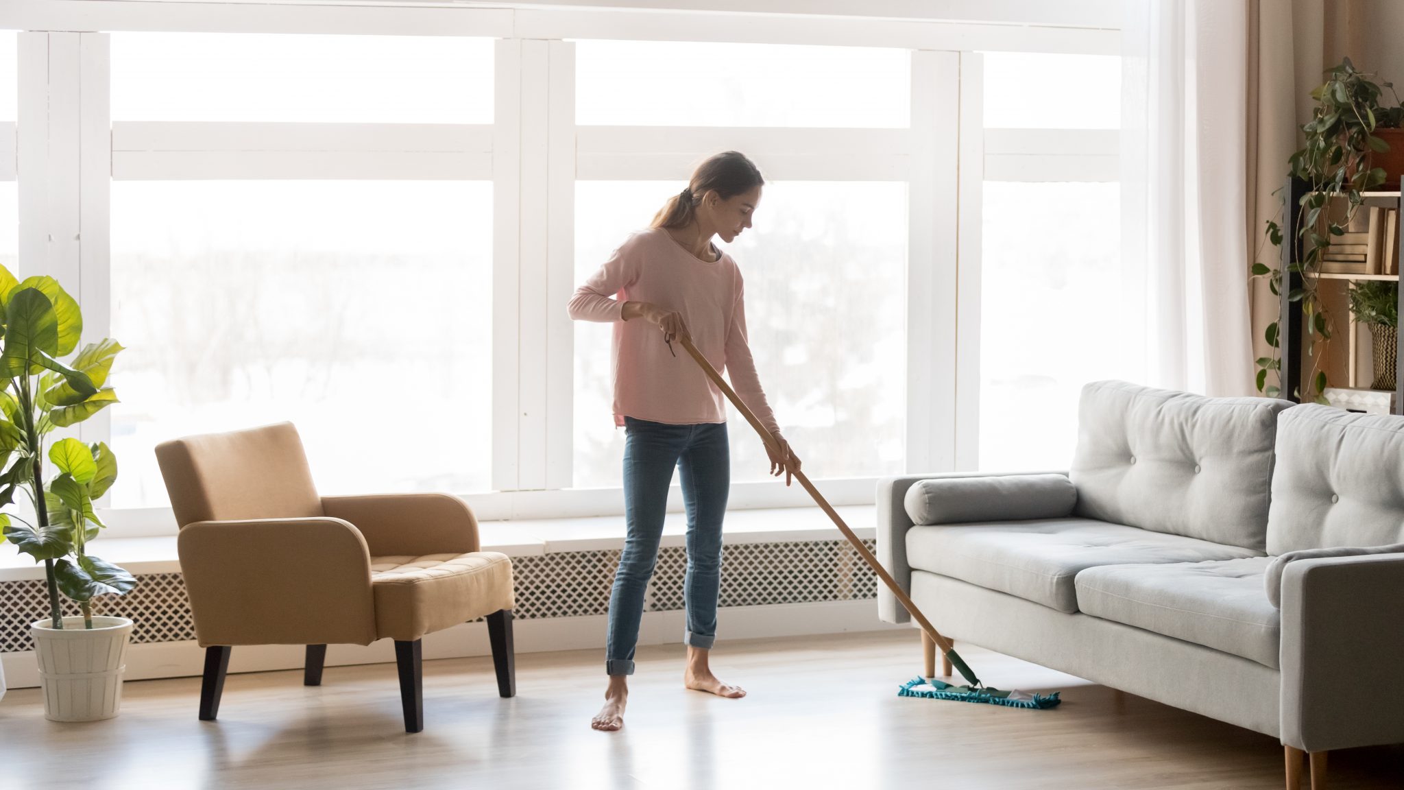Young woman housewife clean floor in modern living room