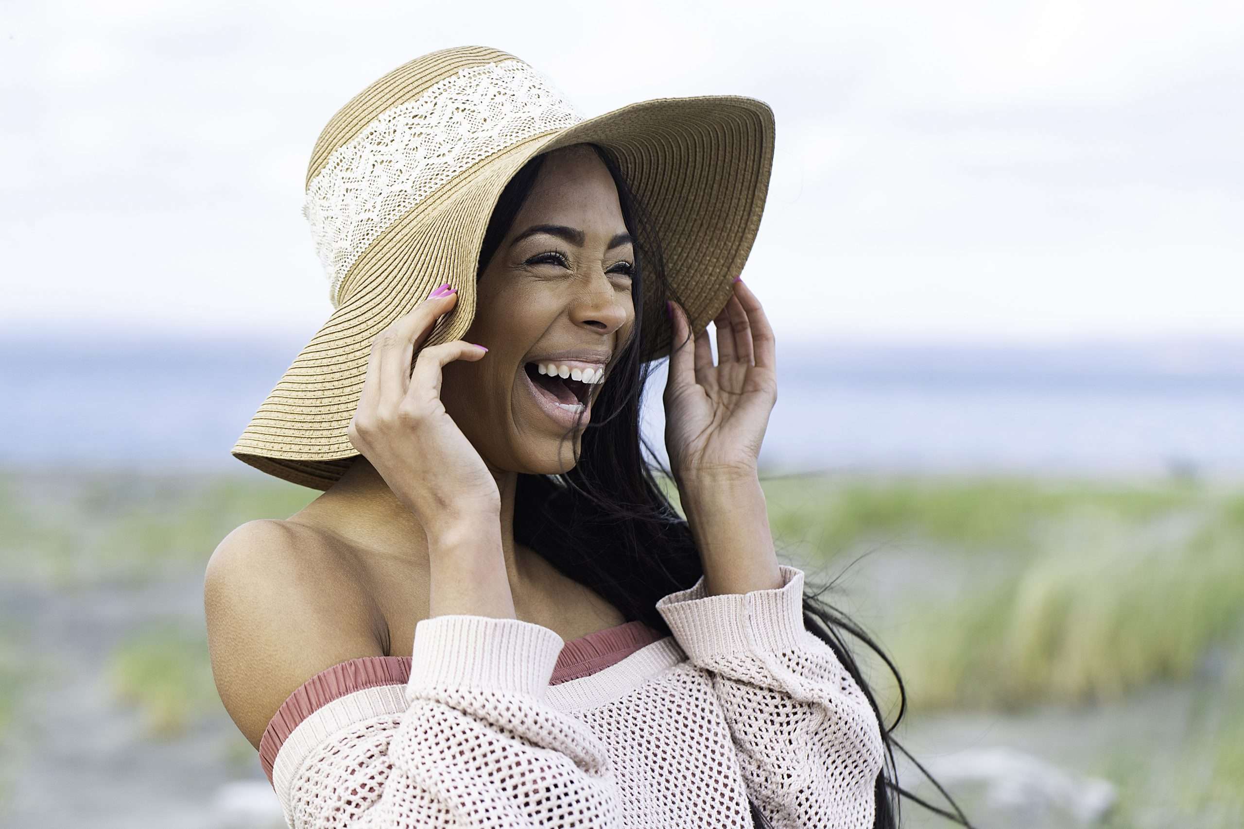 Happy African American woman wearing floppy hat at the beach