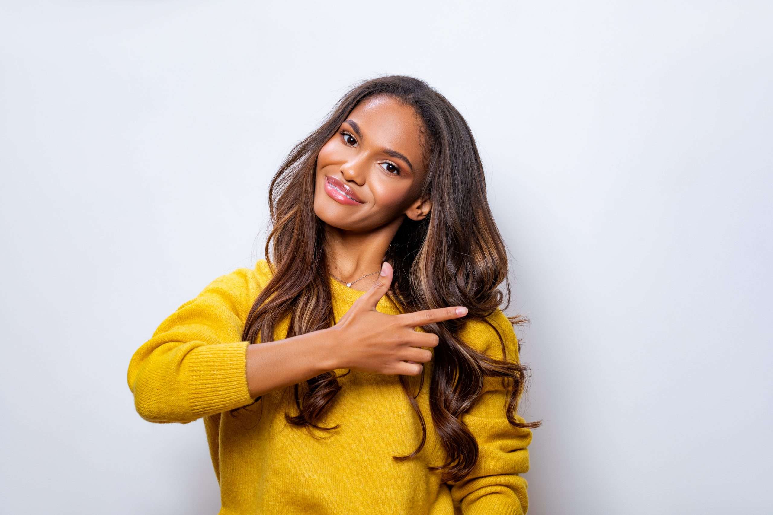 Beautiful black young woman in yellow sweater pointing with hand