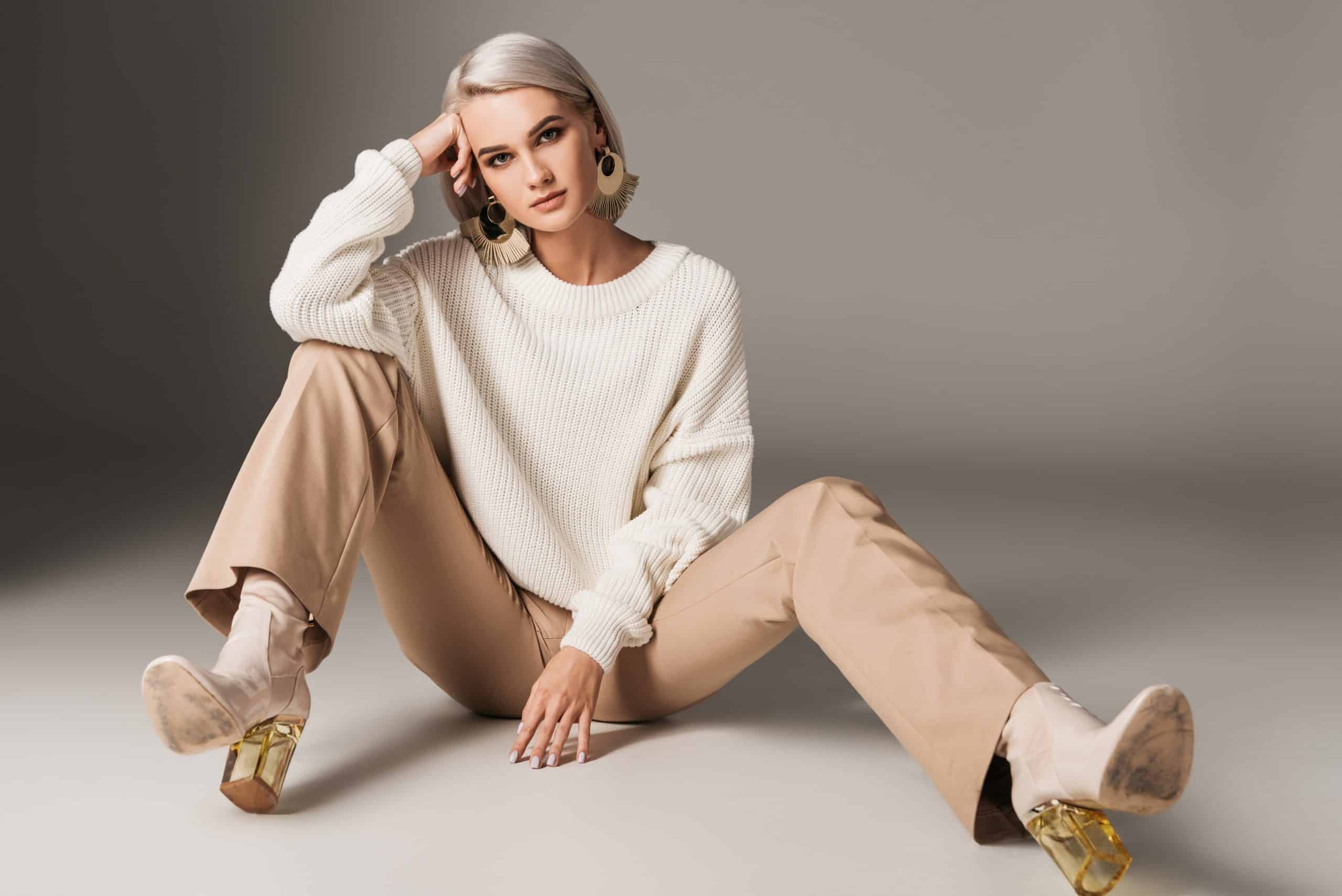 fashionable female model posing in white sweater, beige pants and autum