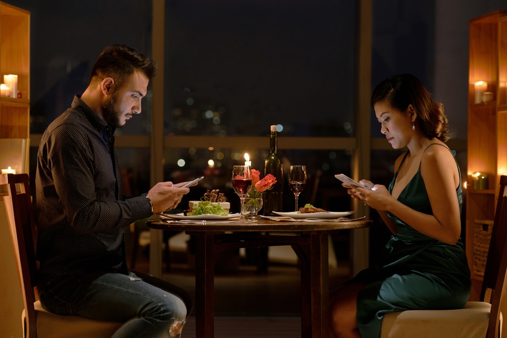 Young,People,Checking,Their,Smartphones,During,Romantic,Date,In,Restaurant