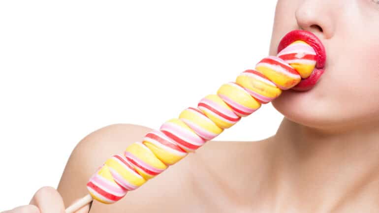 Close-up shot of woman's mouth bright red lips with lollipop