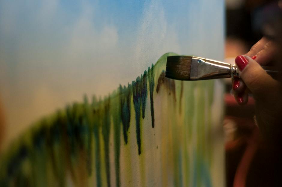 A photo of a person holding a paintbrush in front of a canvas, symbolizing the process of crafting a visual narrative for a dating profile.